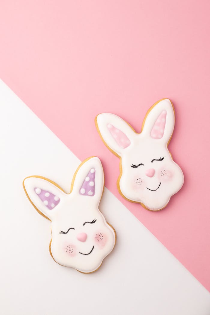 Adorable Easter bunny cookies with pastel icing on a pink and white background, perfect for festive decorations.